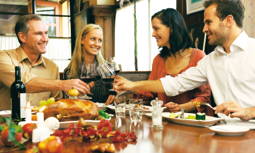 Freunde beim Gansessen und stoßen mit Rotwein an