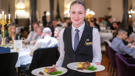 Servicekraft serviert Servicekraft serviert Speisen bei einem Bankett
