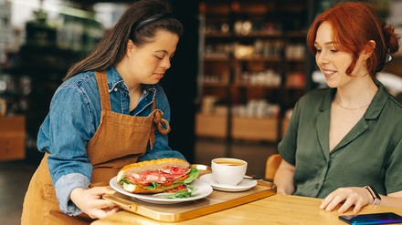 Behinderte Servicekraft Eine Behinderte Servicekraft serviert einen Kaffee und Sandwich