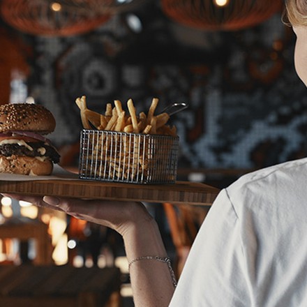 Servicekraft serviert Burger und Pommes Servicekraft serviert Burger und Pommes