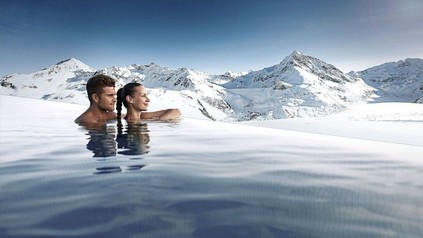 Mann und Frau in Pool blicken auf Bergpanorama