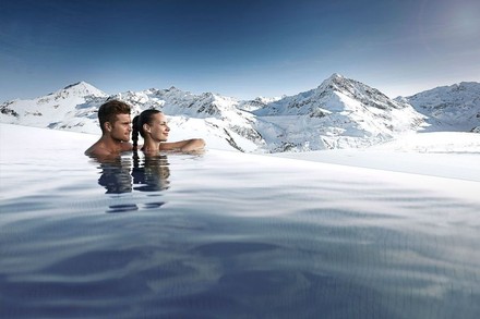 Mann und Frau in Pool blicken auf Bergpanorama