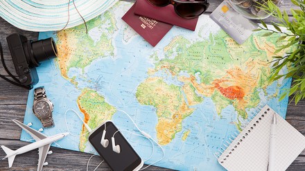 Weltkarte mit Flugzeug, Sonnenbrille, Handy, Kopfhörer und Reisepässen