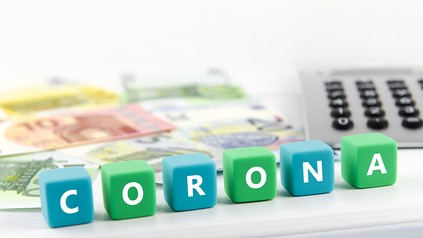 Buchstabenwürfel mit dem Wort Corona, Geldscheine und ein Taschenrechner