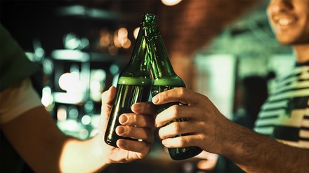 Zwei Männer stoßen mit Bierflaschen an