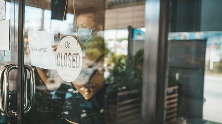 Junge Frau mit Mundschutz schließt ein Restaurant oder Café