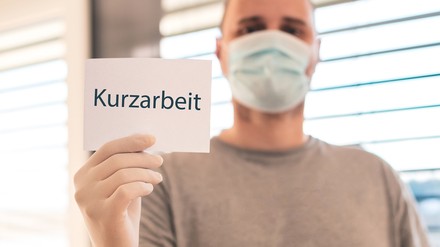 Ein Mann mit einem Schild mit der Aufschrift Kurzarbeitt
