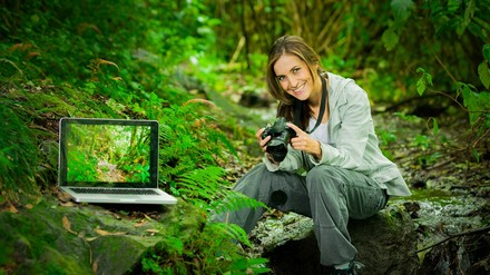 Eine Frau mit einem Laptop im Wald