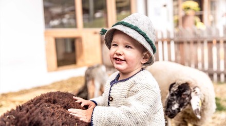 Kind streichelt lachend ein Schaf