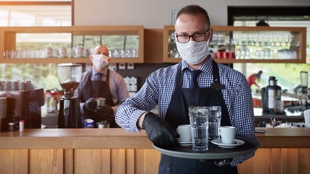 Servicekraft mit Maske und vollem Tablet