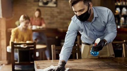Kellner putzt Tisch ab