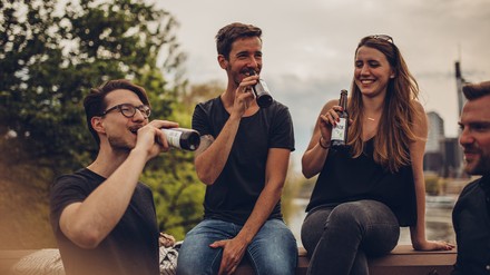 Gruppe Menschen sitzt bei einander und trinkt Bier