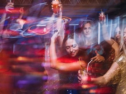 Tanzende junge Damen auf einer Party, mit Gin-Gläsern in der Hand