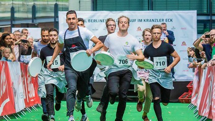 Kellern mit Tabletts in der Hand liefern sich ein Rennen
