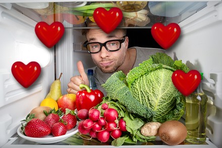 Ein Mann blickt in einen Kühlschrank voller Lebensmittel