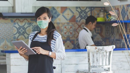 Kellnerin im Restaurant oder Café mit Mundschutz und Tablet