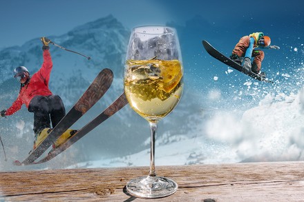 Zwei Skifahrer und im Vordergrund ein Glas Wein