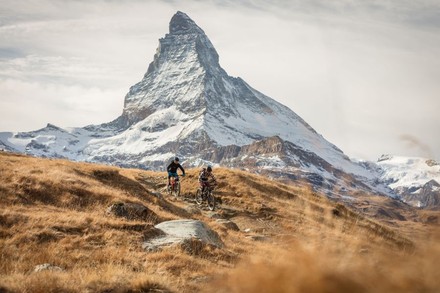 Zwei Mountainbiker auf Tour, im Hintergrund ist das Matterhorn zu erkennen