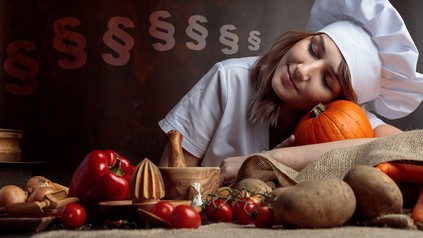 Eine Köchin liegt mit dem Kopf auf dem Tisch und schläft