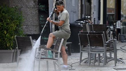 Frau sprüht verdreckte Stühle mit dem Hochdruckreiniger sauber