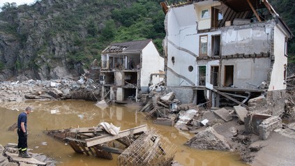 Ein Feuerwehrmann steht im Dorf Mayschoß vor einem völlig zerstörten Haus.