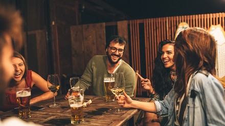 Gruppe junger Leute sitzt draußen und trinken Bier und Wein