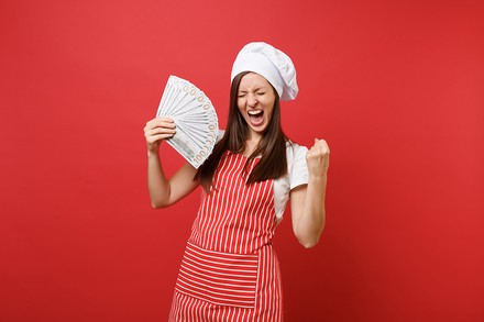 Eine Köchin mit einem Bündel Geldscheine in der Hand