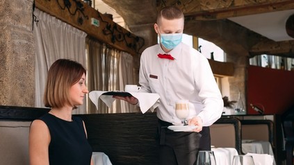 kellner mit Schutzmaske beim Servieren
