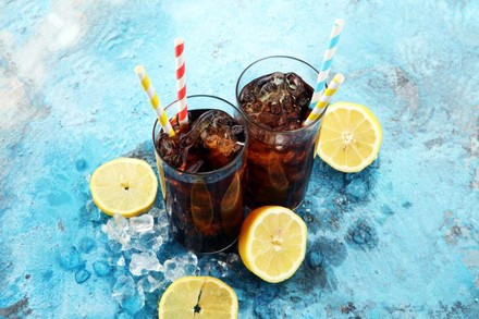 Zwei frische Gläser mit Cola, Eiswürfen und Zitronen