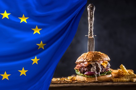 Eine EU-Flagge und ein Burger, in dem ein messer steckt