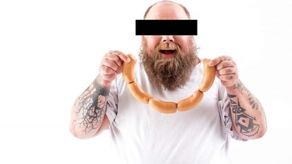 Mann mit Bart hält Wurst in Händen, das Gesicht ist zensiert