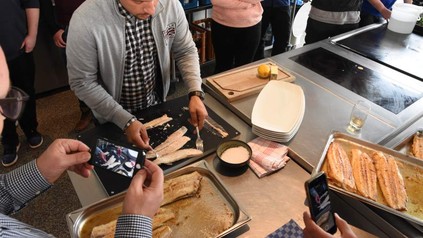 Azubi in Küche bereitet Fisch zu