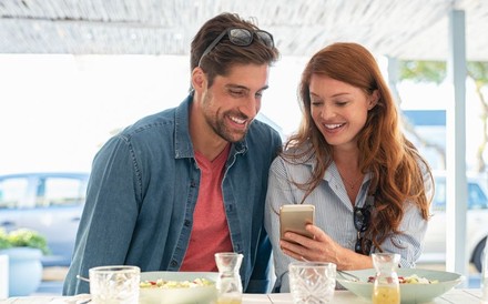 Junges Paar benutzt ein Smartphone in einem Lokal.