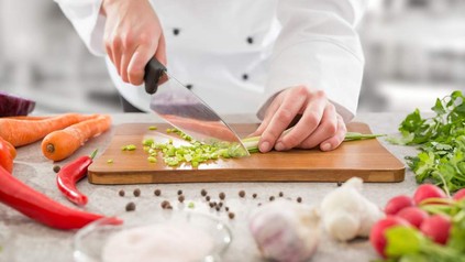 Koch schneidet Gemüse auf Hackbrett