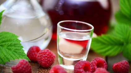 Glas Schnaps, davor Himbeeren