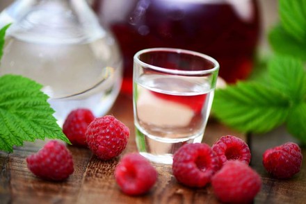 Glas Schnaps, davor Himbeeren