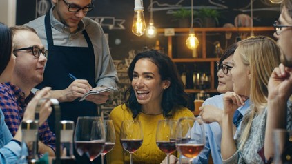 Freundesrunde in einem LOkal gibt eine Bestellung auf