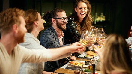 Gruppe von Freunden, die gemeinsam beim Essen im Restaurant anstoßen