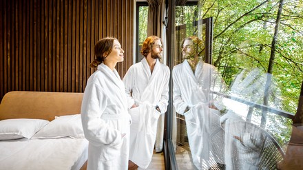 Junges Paar im Hotelzimmer schaut aus dem Fenster in die Natur