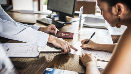 Ein gast füllt an einer Hotelrezeption einen Meldeschein aus.
