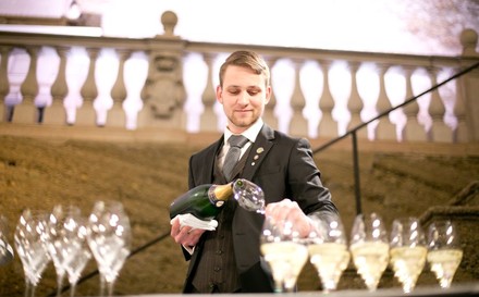 Sommelier schenkt Sektgläser ein