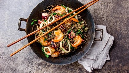 Ein asiatisches Fischgericht in einem Wok mit Essstäbchen