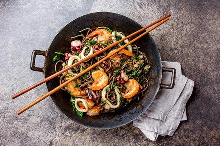 Ein asiatisches Fischgericht in einem Wok mit Essstäbchen