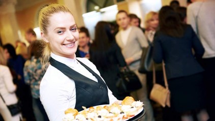 Eine junge Servicekraft verteilt Häppchen bei einer Veranstaltung