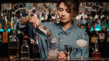 Frau hinter der Bar mixt einen Cocktail