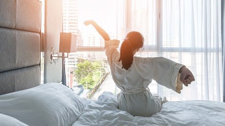 Frau streckt sich nach dem Aufwachen im Hotelbett