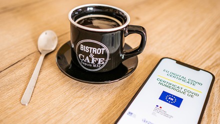 Impfnachweis neben Kaffeetasse