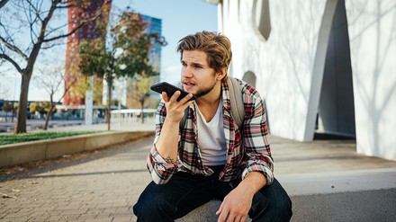 Junger Mann nimmt Sprachnachricht am Handy auf