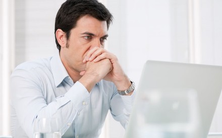 Ratloser Mann sitzt vor Laptop