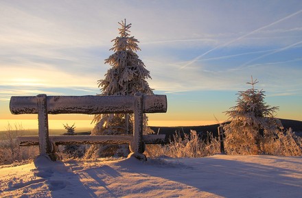 Eine verschneite Bank auf einem Berg mir prächtiger Aussicht